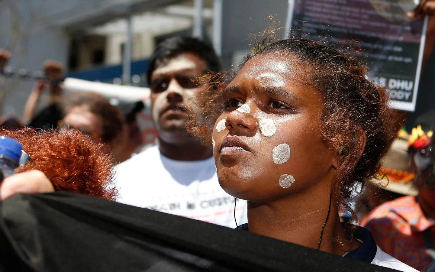 An Aboriginal woman holds a banner with other march participants behind her.