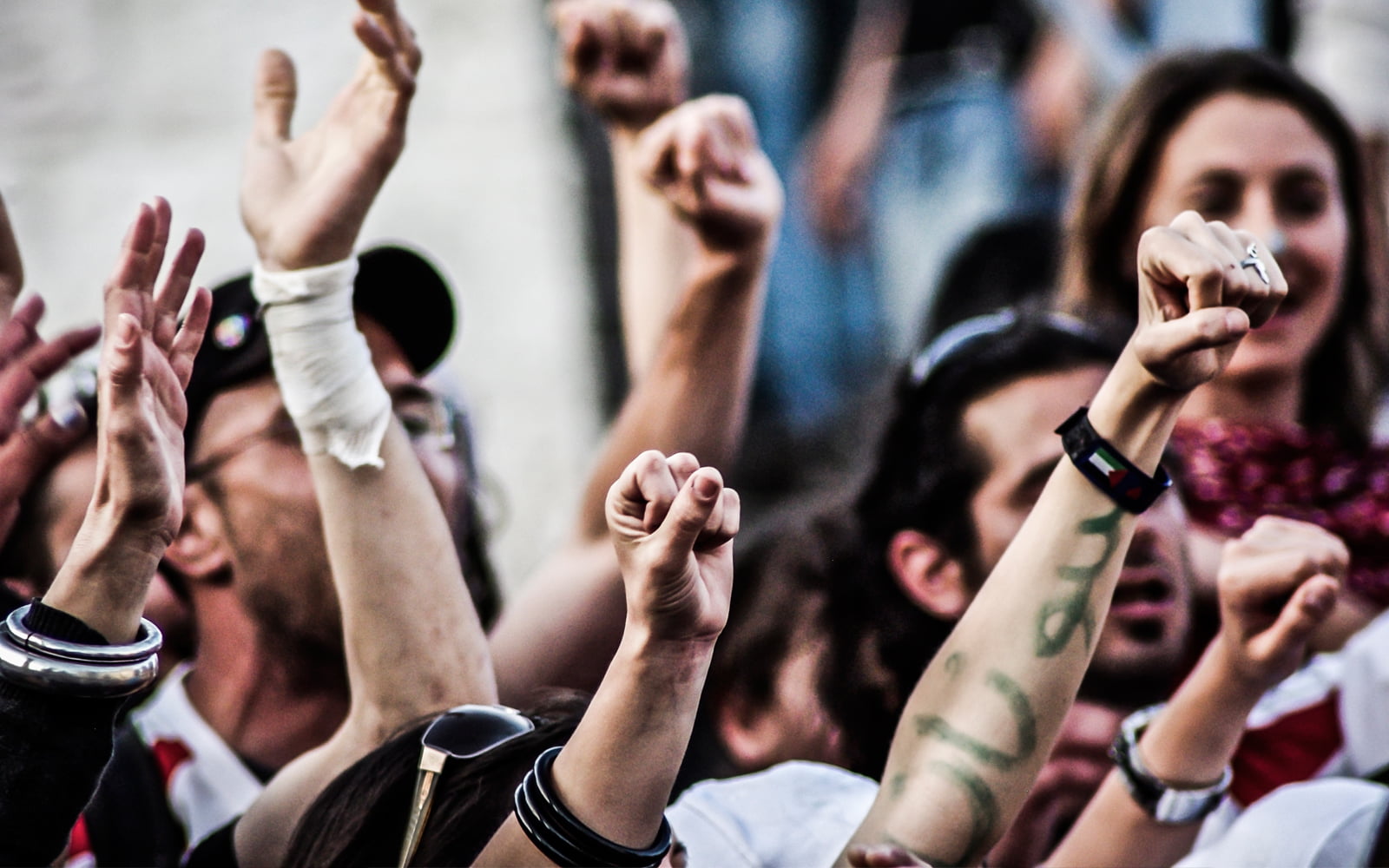 A jubilant multinational crowd, with hands in the air, cheering