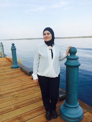 A woman standing on a jetty looking into the distance with the sea in the background