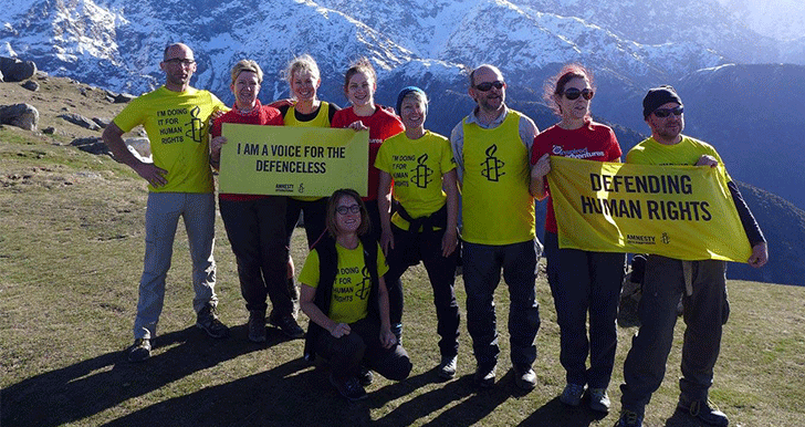 a group of people standing in front of mountains waring amnesty tshirts