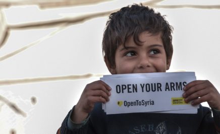 A young boy holding a Open to Syria campaign sign
