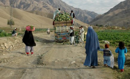 A woman and her family walking behind a cart in rural Afghanistan