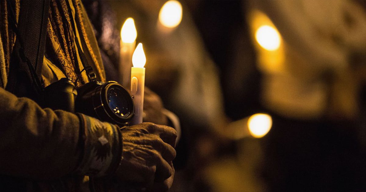 An activist holds a camera and a candle at a vigil