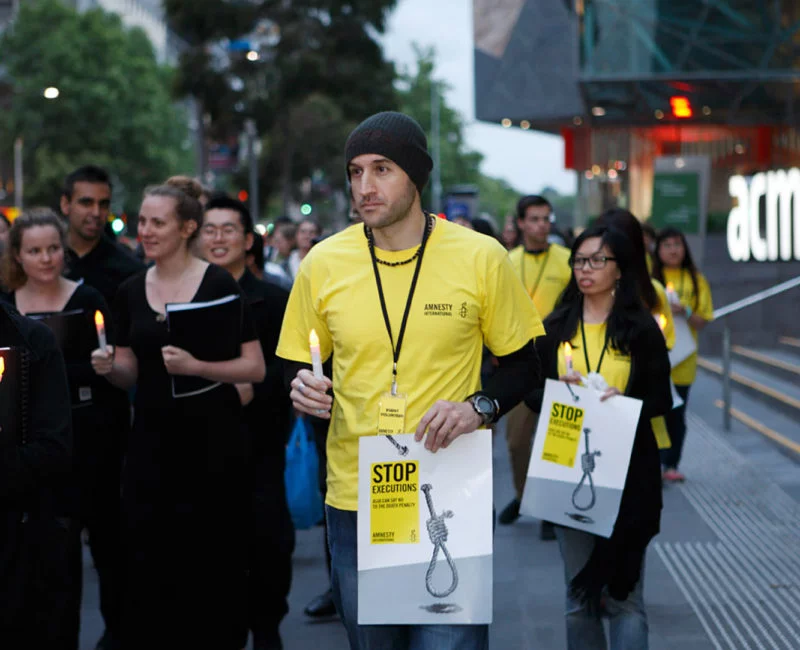Protesters with candles and posters at a rally against death penalty