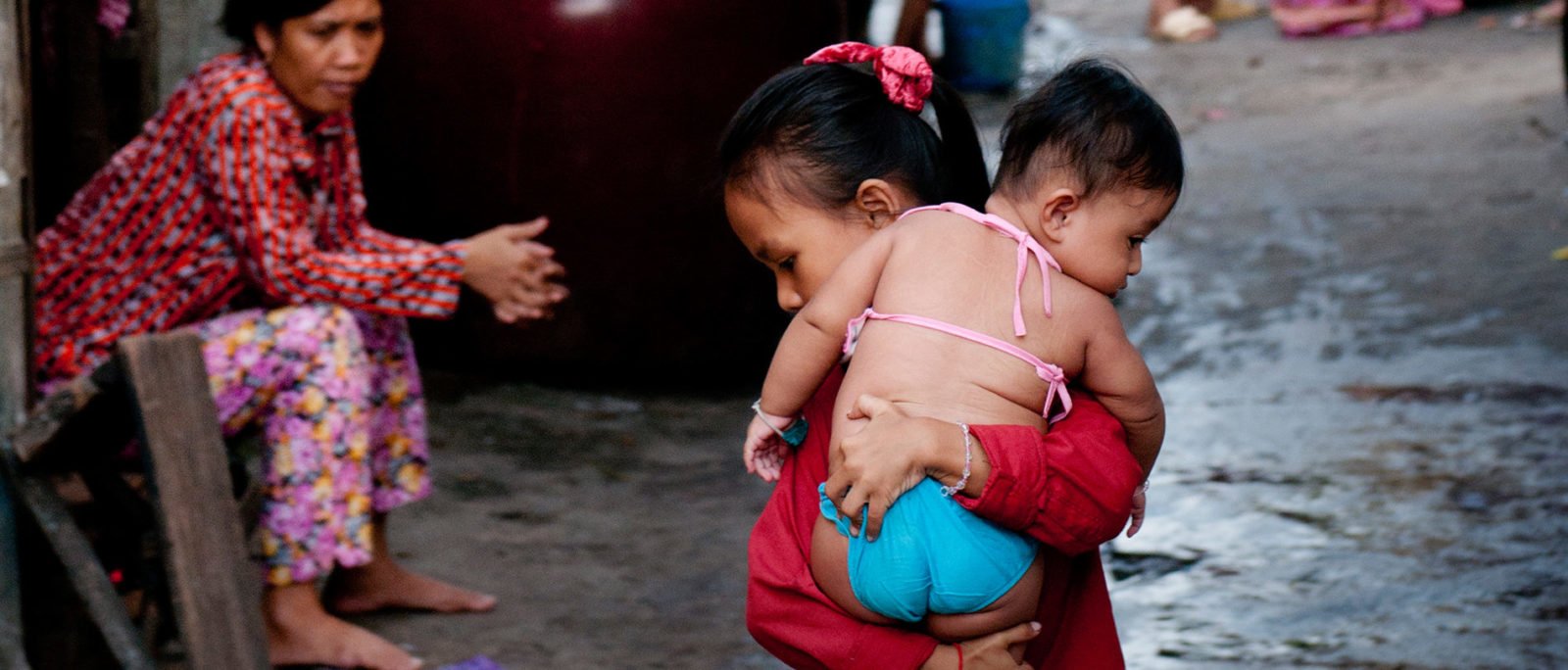 A young girl carries a baby through the street in Boeng Kak Lake, Phnom Penh, where families have been forcefully evicted due to corporate development projects.