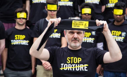 Amnesty protesters with Stop Torture T-shirts and blindfolds at a rally.