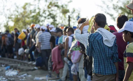 A long line of refugees, many holding personal possessions, waiting at the Greece-Macedonian border.