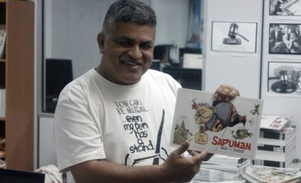 Malaysian political cartoonist Zunar holding up some of his work