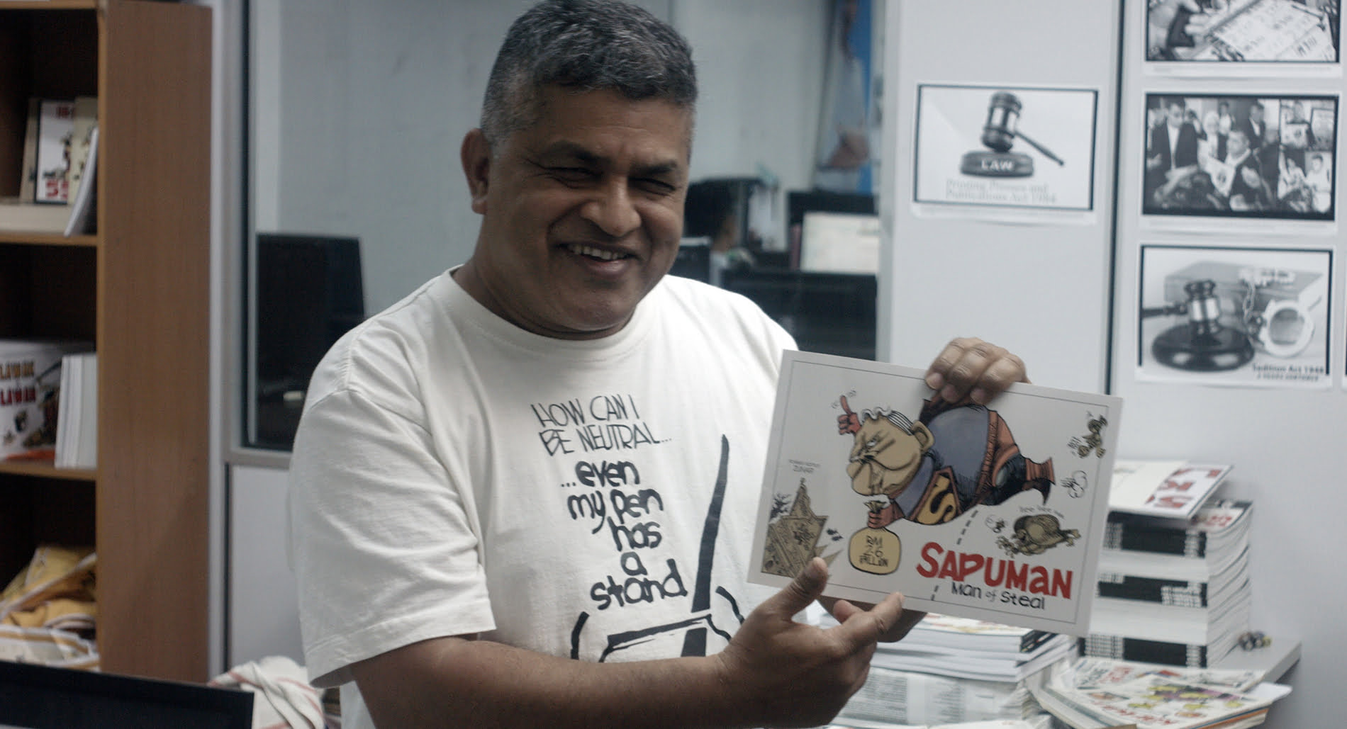 Malaysian political cartoonist Zunar holding up some of his work