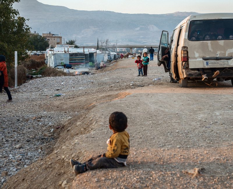 Syrian boy sits on a roadside in Lebanon