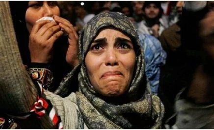 A woman cries at a protest with her arms raised in Tahrir Square after it is announced that Egyptian President Hosni Mubarak was giving up power. Tahrir Square, Egypt, 2011.