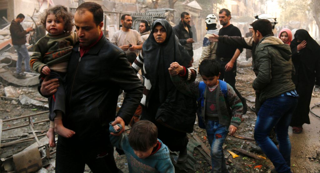 Syrians make their way through debris after air strikes in the rebel-controlled side of Aleppo on January 13, 2016.