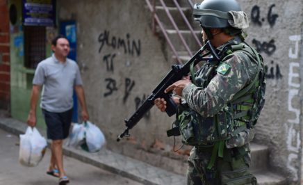 a man in miltary uniform standin in the street with a large gun