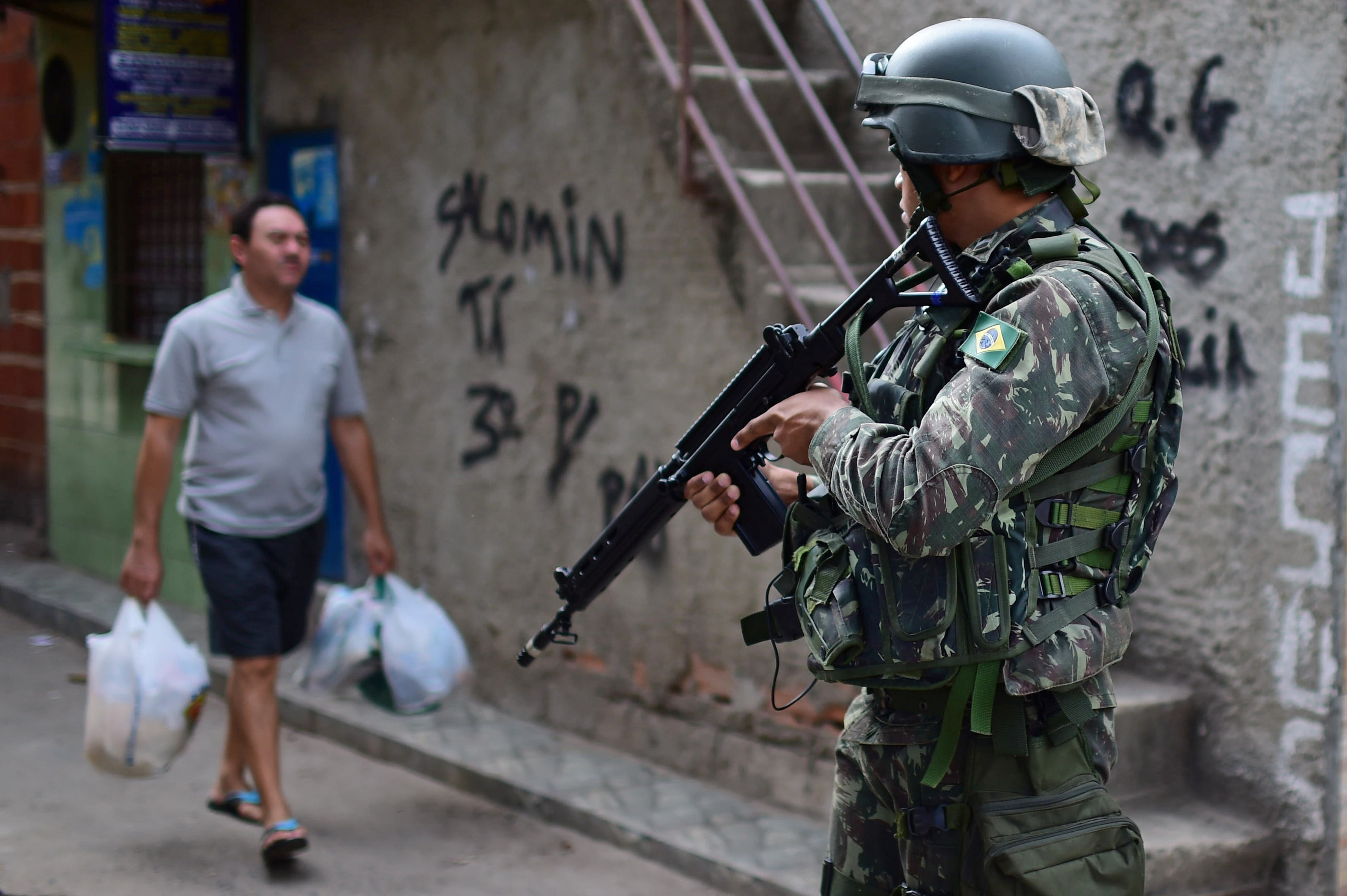 a man in miltary uniform standin in the street with a large gun 