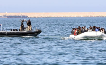 Libyan coast guards escort a boat along the coastline.
