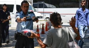 A Turkish police points his gun to a woman, asking her to leave the package she is carrying, in front of the courthouse in Ankara, on July 18, 2016, as some 7500 people have been detained in Turkey and almost 9000 officials sacked three days after a failed coup which has stunned the country.