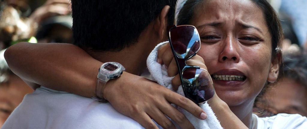 Relatives of Michael Siaron grieve during his burial ceremony at a cemetery in Manila.