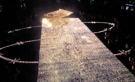 Amnesty supporters build the AI logo out of 26,105 candles in Belgium.