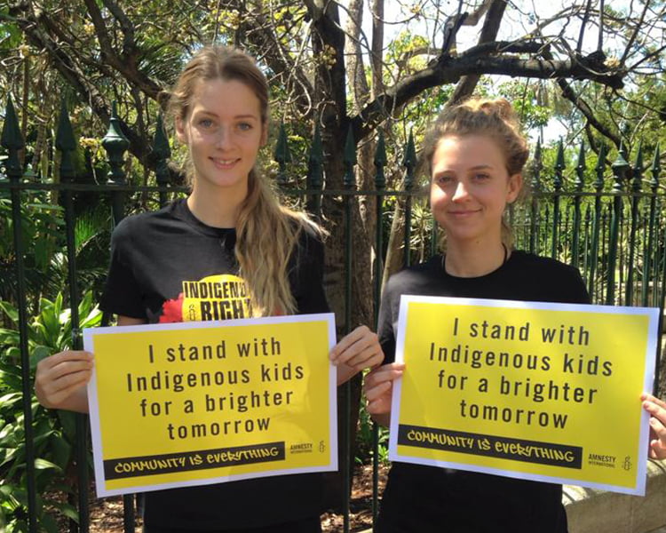 Activists hold placards declaring that they stand with Indigenous kids for a brighter tomorrow