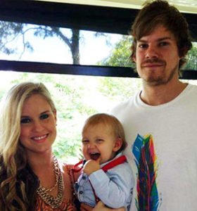 A woman and man holding a baby between them