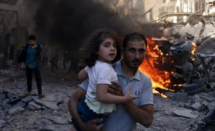 A man carries a young girl through rubble in Syria.