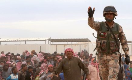A Jordanian soldier stands guard as Syrian refugees arrive to a camp