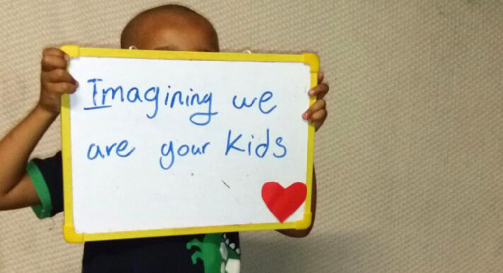 A child in the Refugee Processing Centre on Nauru holds sign that reads "Imaging we are your kids". © Private