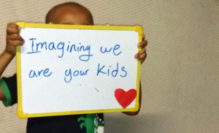 A child in the Refugee Processing Centre on Nauru holds sign that reads 