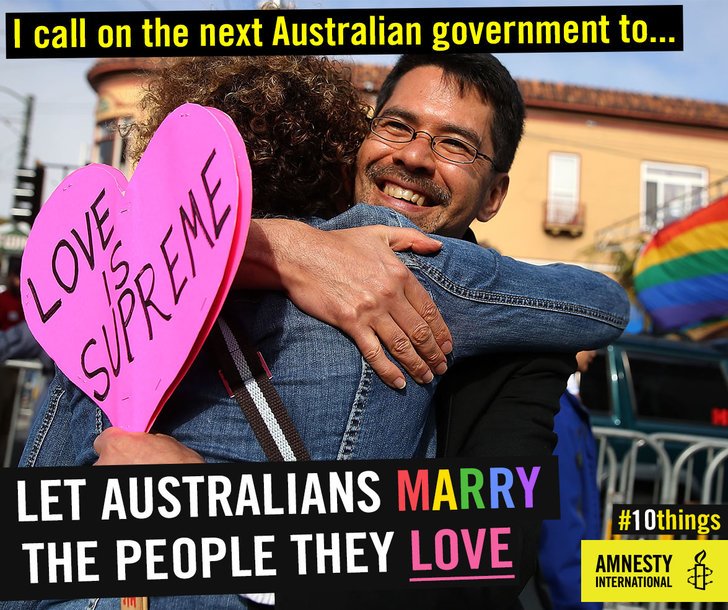 Two people hugging holding love heart placard