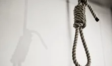 A noose hangs in front of a white wall
