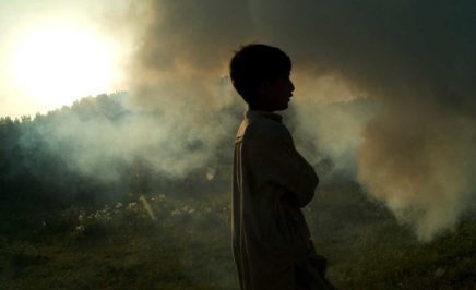 A young boy walks through clouds of smoke at the Sheikh Shehzad camp