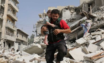 A man and his child behind a bombed building