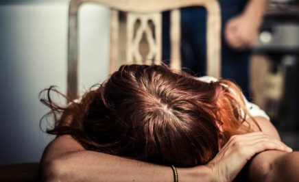 A woman with her head on a table and a man in the background