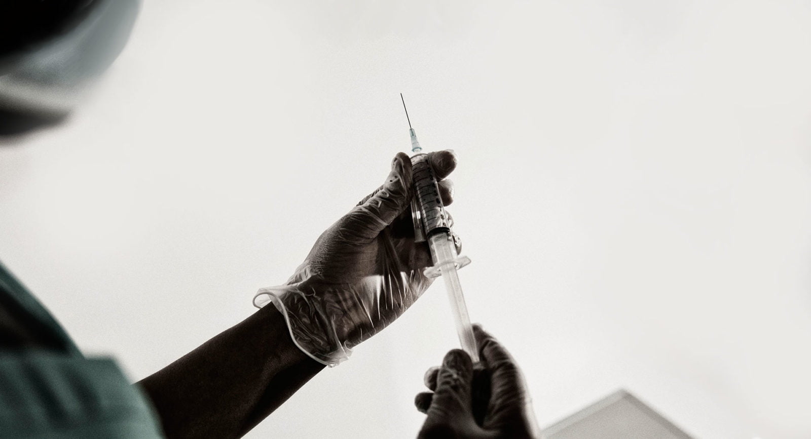 A gloved hand holding a syringe. © Amnesty International