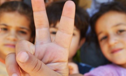 Syrian refugee children making the 'peace' sign with their hands. © Flickr/Trocaire