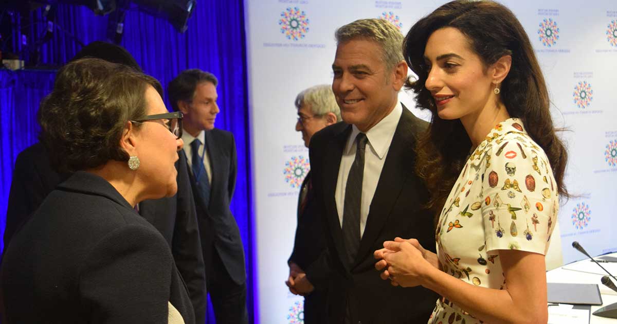 George Clooney and others in a group talking in front of a camera