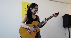 A woman playing guitar at a Northcote local group event.