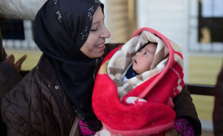 Syrian refugee woman holds her baby.