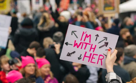A hand holds up a sign that says 