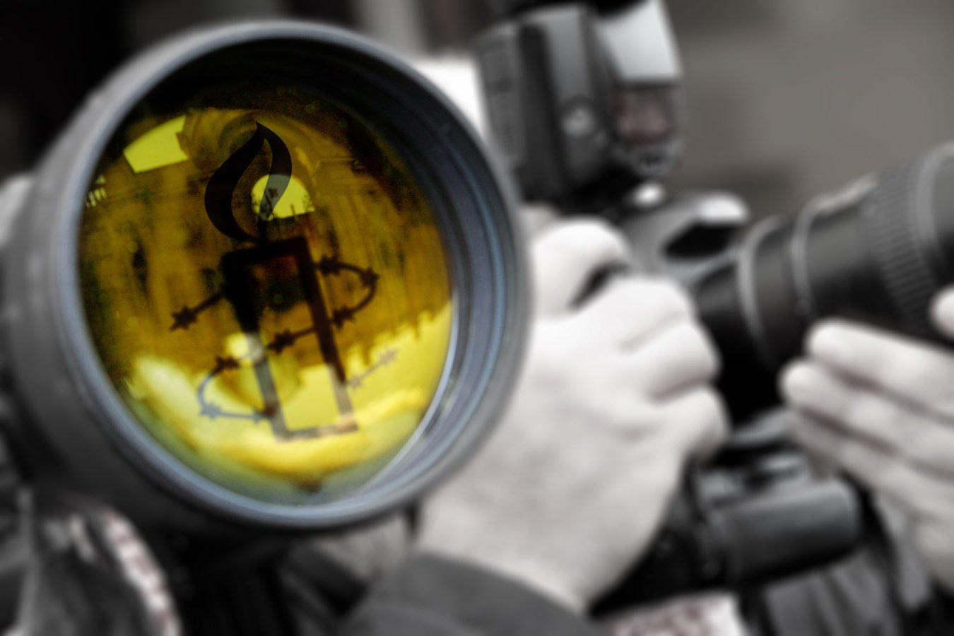 This is an image of a camera lens with a yellow Amnesty candle reflected in it. It was created as a youtube header image.