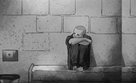 A photo of a black and white illustration of a child sitting on a bed in a prison cell, resting his head on his knees.