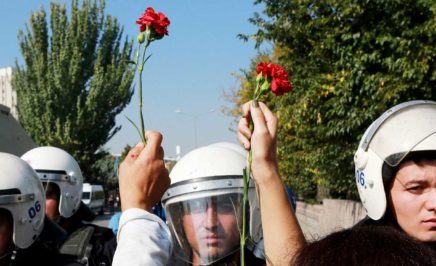 People hold carnations in front of riot police during clashes in Turkey