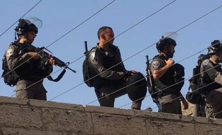 Armed guards stand on top of a wall.