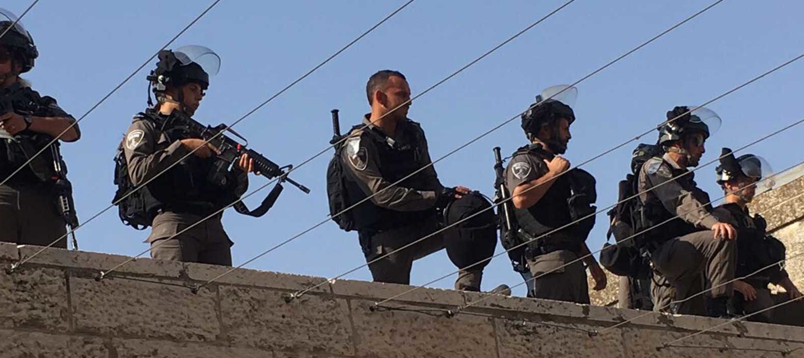 Armed guards stand on top of a wall.