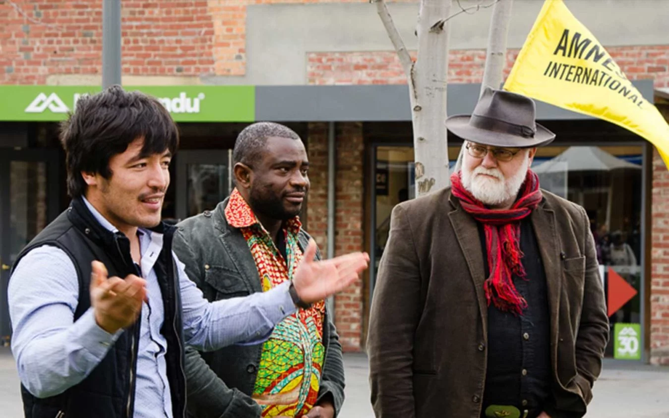 Alderman Bill Harvey from Hobart City Council, John Kamara from the Sierra Leone community and Haji Alizada a local Hazara man, opening the tree for the Tasmania Refugee Group's event
