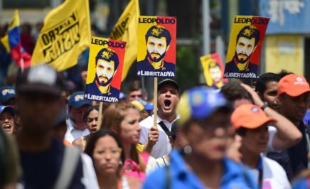 a large group of protesters holding banners and walking down a street