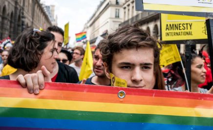 A young boy hold a rainbow flag in a crowd