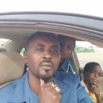 Mahadine, an online activist imprisoned in Chad, sits in his car with his sons.