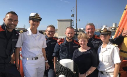 Claire Mallinson with members of the Italian Coast Guard who work to protect people at sea. © AI