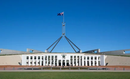 A photo of Parliament House in Canberra, set against a deep blue sky